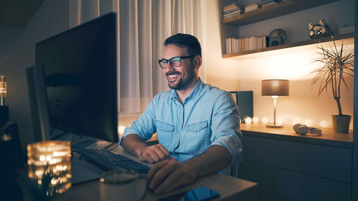 ホームオフィス環境において最新のデスクトップ PC で作業する人
