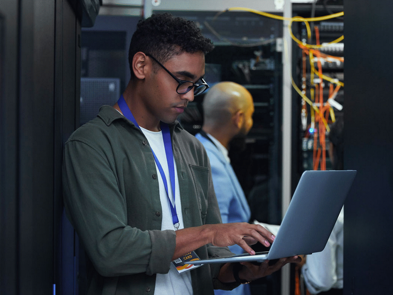 An IT worker with a laptop in a server room.