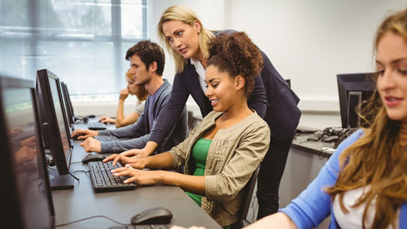 Female individual helping a student on a computer