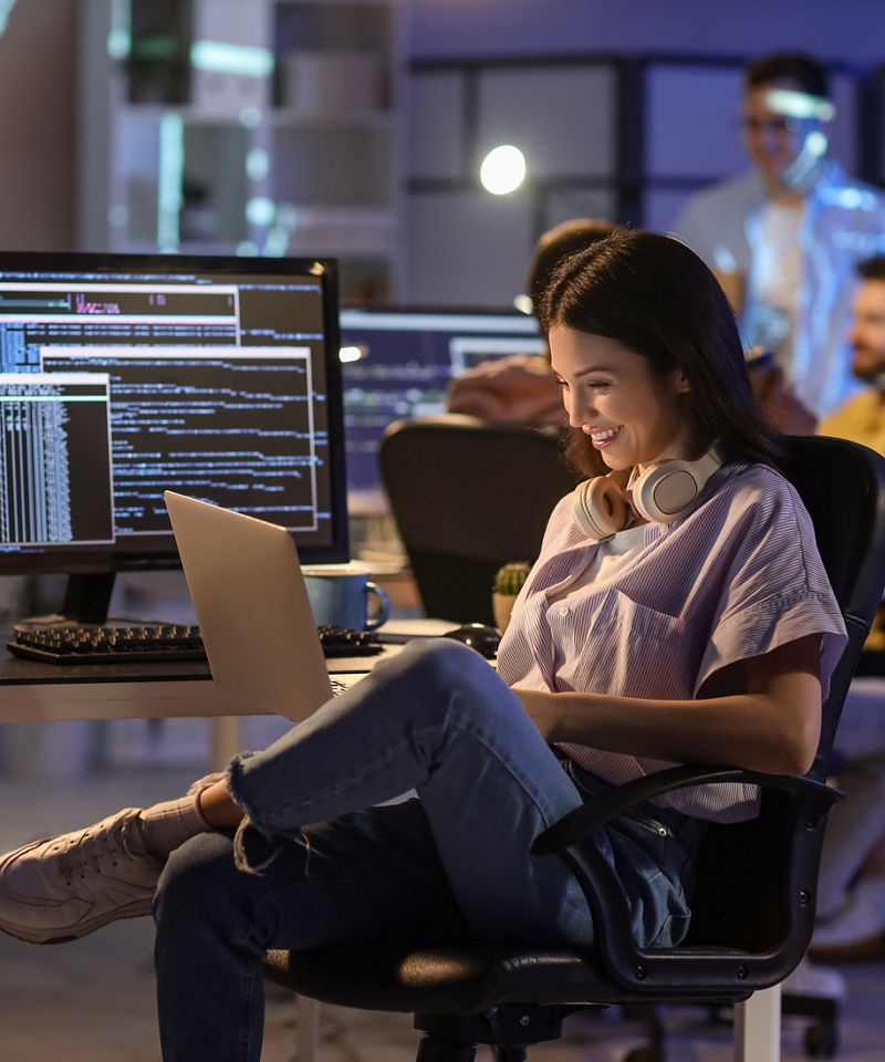 Smiling worker in an office setting, on a laptop.