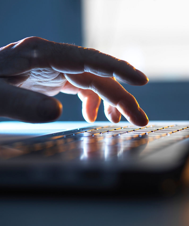 Worker’s hand typing on a laptop keyboard.