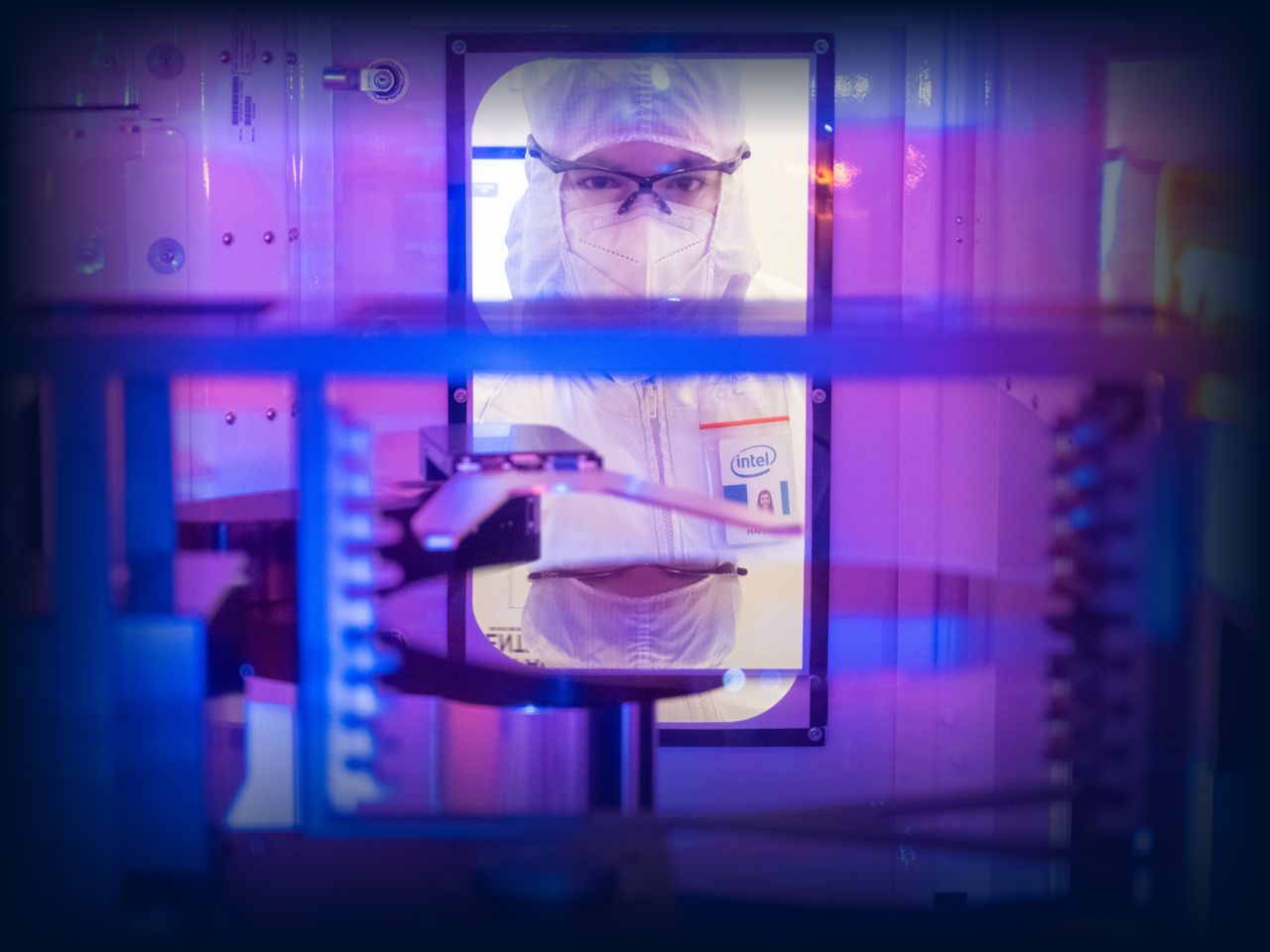 Person holding an Intel processor chip inside a semiconductor facility.
