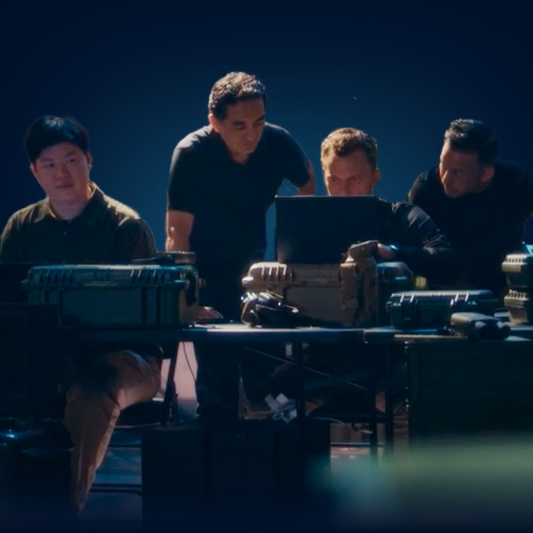 Four people gathered around equipment on a table.