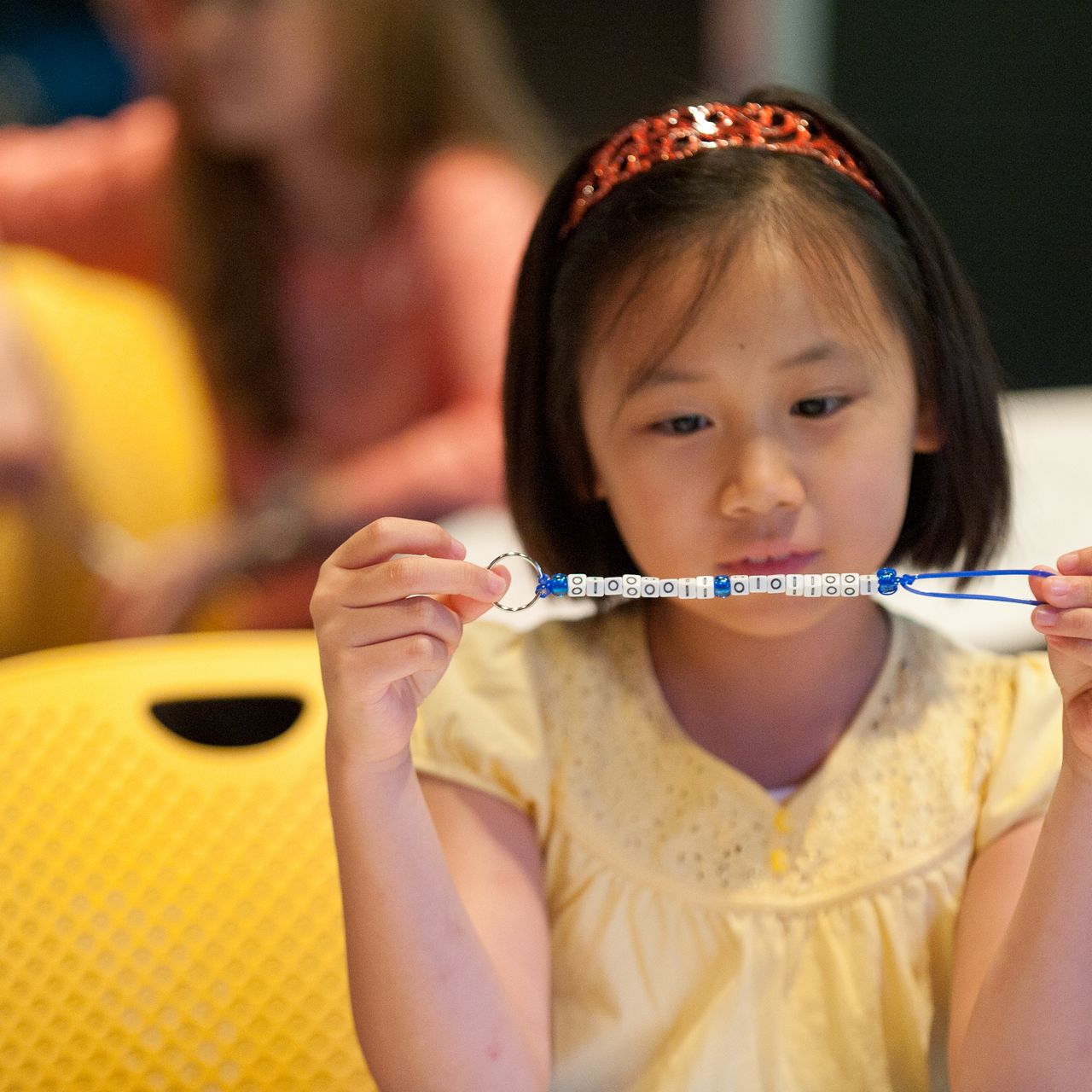 Young girl making a bracelet