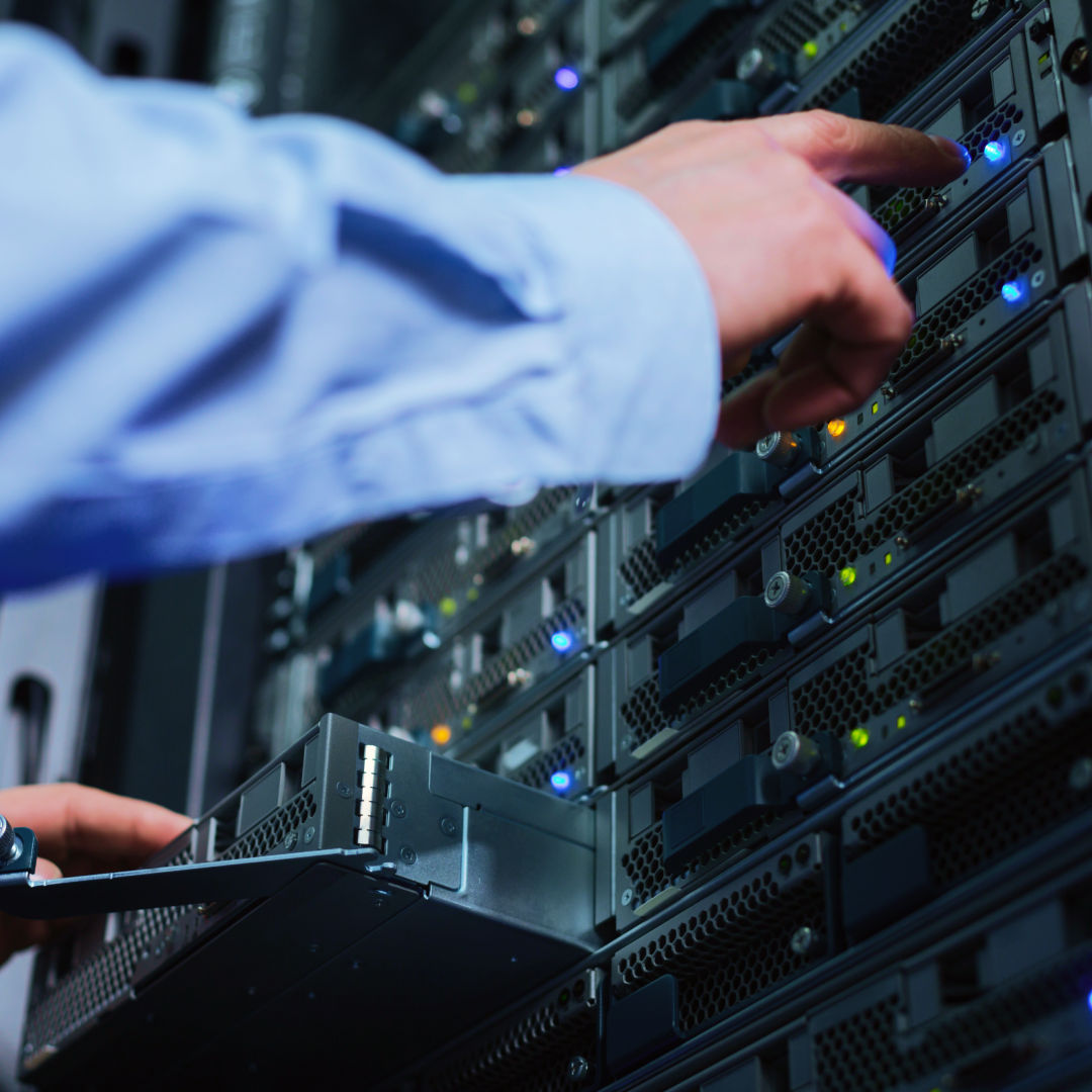 A technician pointing at the blinking lights on a server rack.